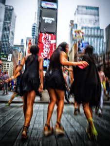 Fest og ballade på Times Square. Billedet er rystet af bevægelse, kvinderne er dullet op til fest, og der er knald på farverne. Essensen af Times Square.
