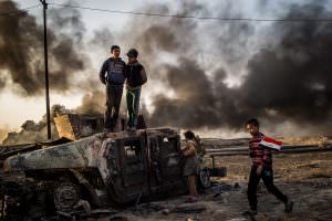 Fight for Mosul. Taha Sirhan, 11, carrying the Iraqi flag through burned out oil fields in the city of Qayyarah south east of Mosul in Iraq. His dad was killed by ISIS during the occupation because he was working for the Iraqi police. Foto: Asger Ladefoged.